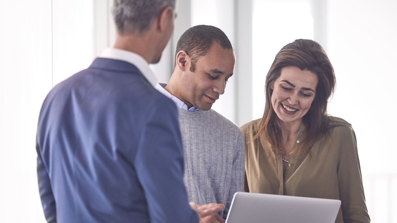 a female and two male professionals looking at data on a laptop