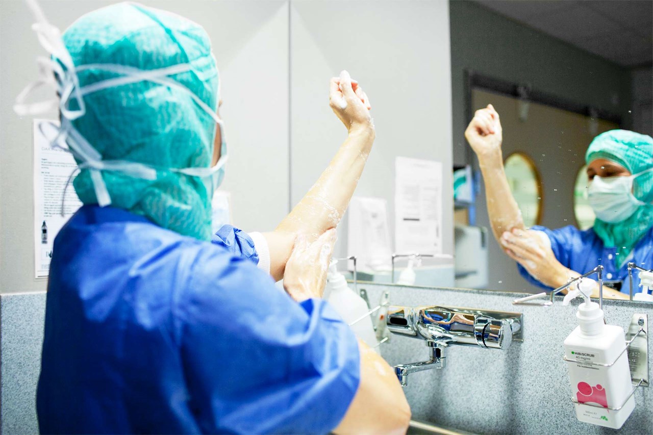 Healthcare professional washing hands in front of mirror