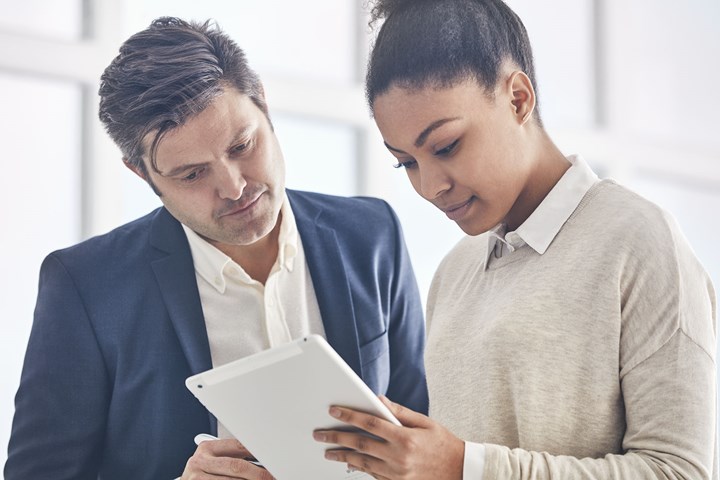 a female and a male professional reading data on a tablet