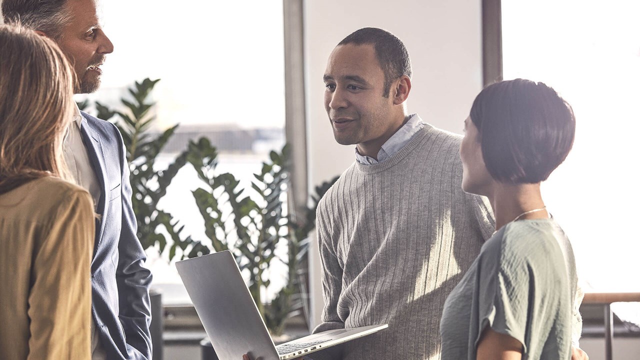 four professionals discussing and holding a laptop